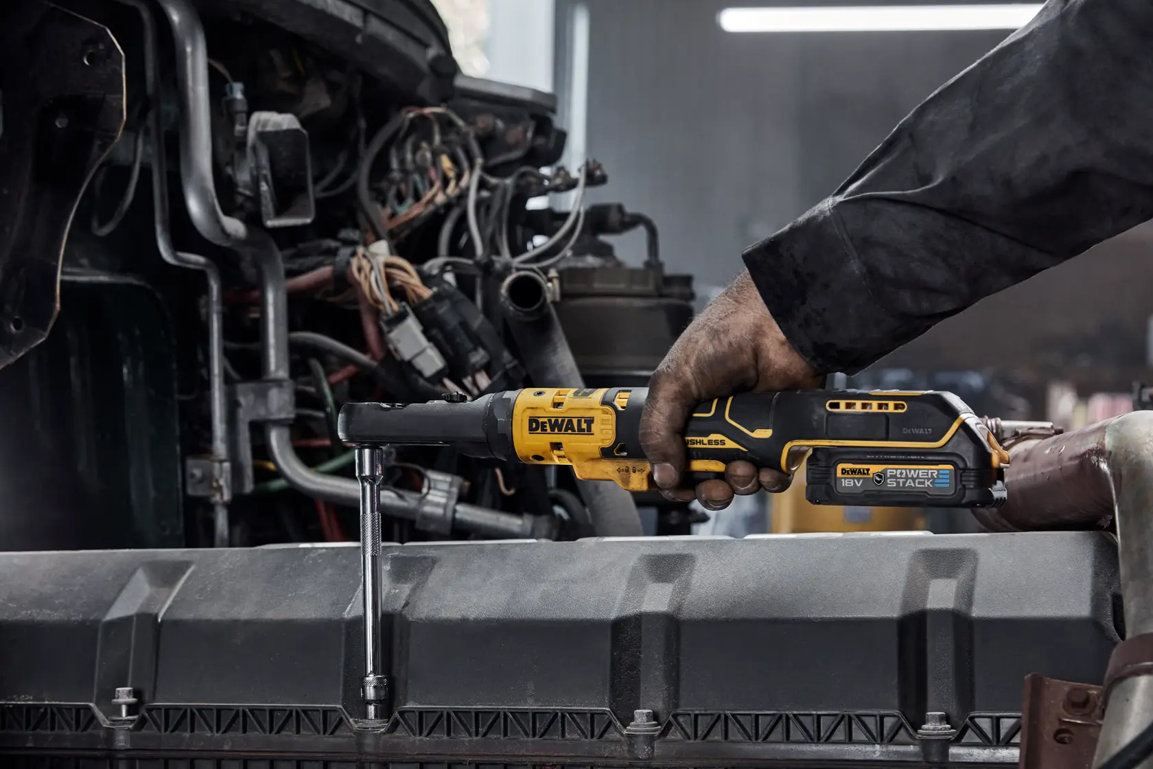Persona usando una herramienta de carraca inalámbrica DEWALT para ajustar un tornillo en un motor.