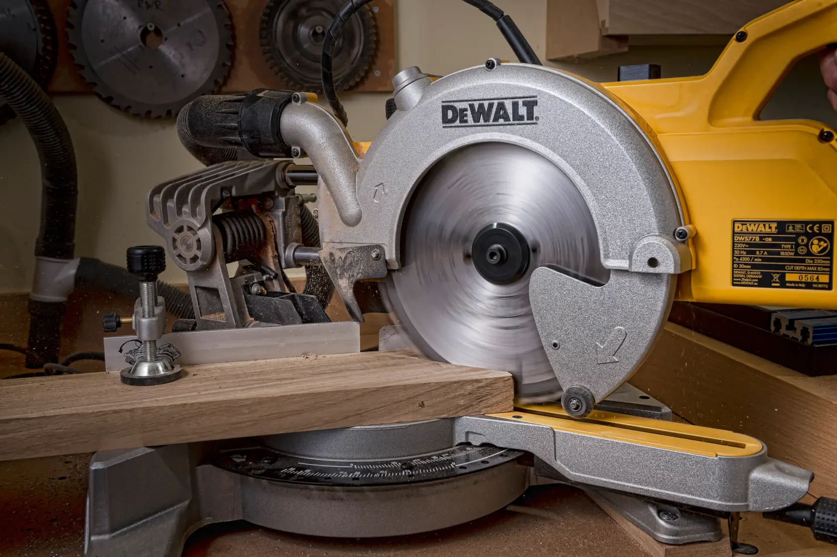 Una ingletadora DEWALT corta madera en un taller. La hoja está girando.