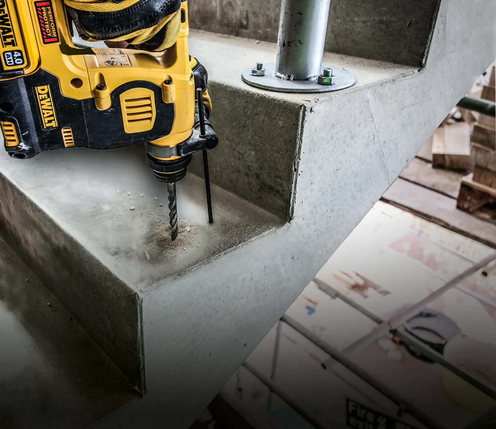 Taladro DEWALT perforando escalera de concreto cerca de soporte metálico en obra.
