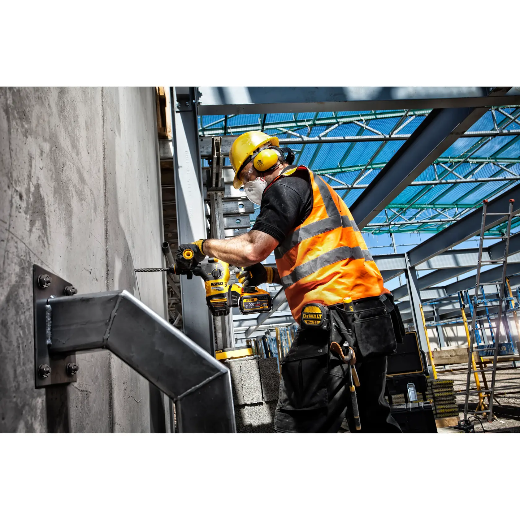 Trabajador perfora pared de hormigón con herramienta DEWALT en obra, lleva equipo de seguridad.